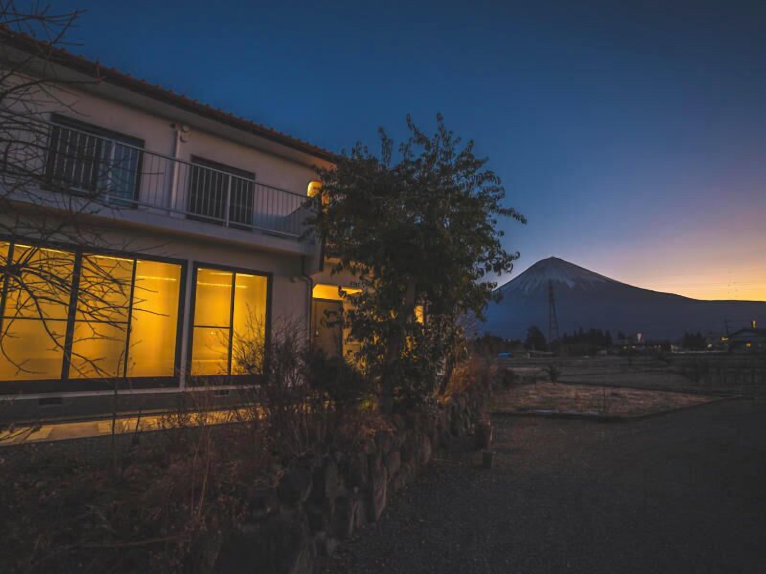 A modern house with large windows and a view of a mountain at dusk.