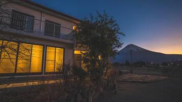 A modern house with large windows and a view of a mountain at dusk.