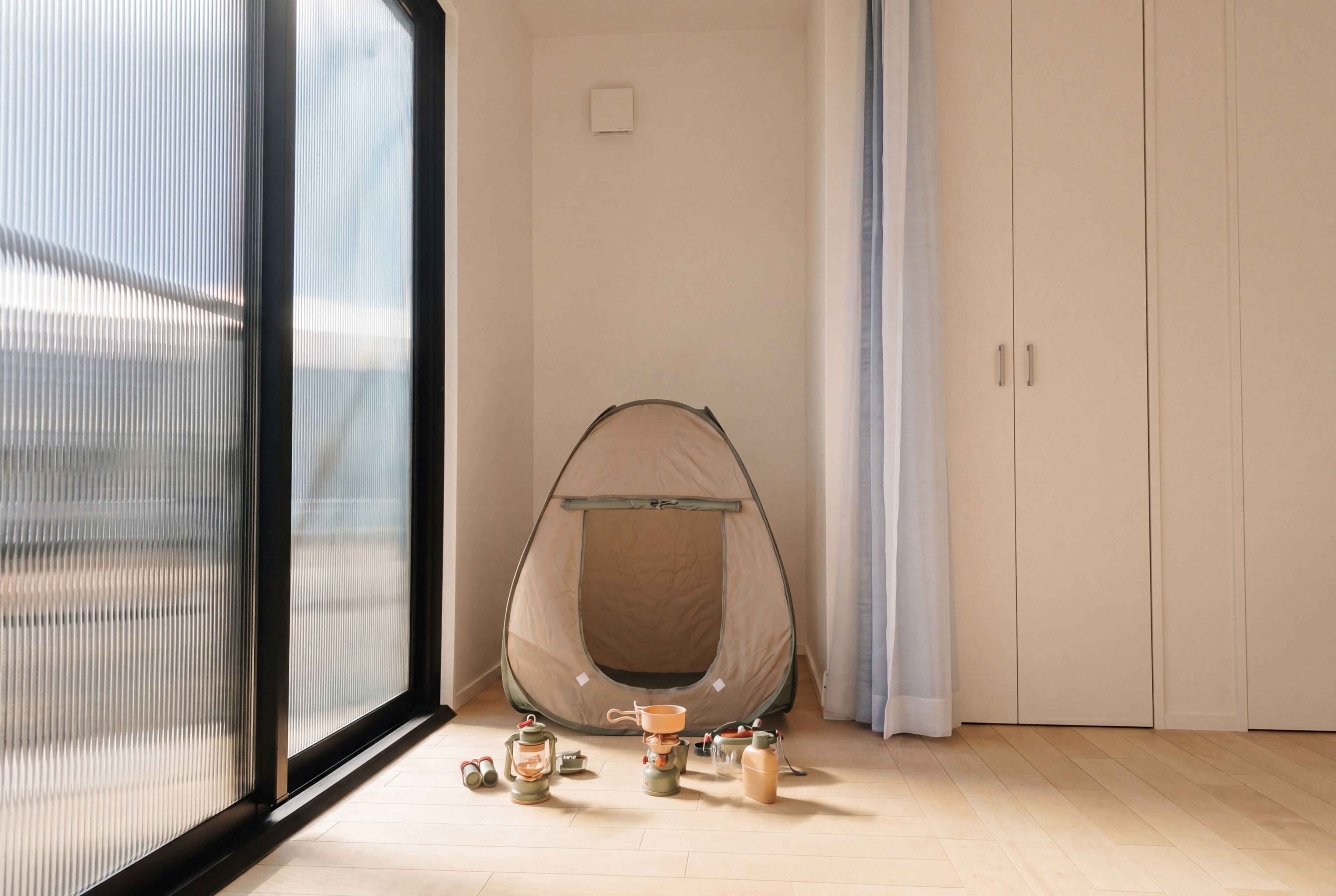 A room with a large window, a tent-like structure, and a wardrobe.