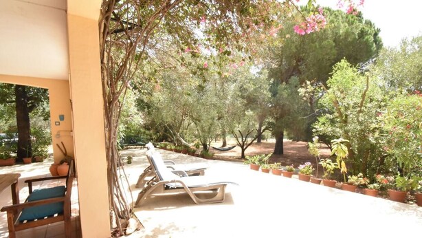 A covered patio with lounge chairs, a table, and potted plants. - Casa Vacanze Il Bouganville (Chia)