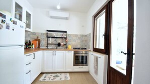 A kitchen with white cabinets, a stainless steel oven, a sink, and a window with a view. - Casa Vacanze Il Bouganville (Chia)