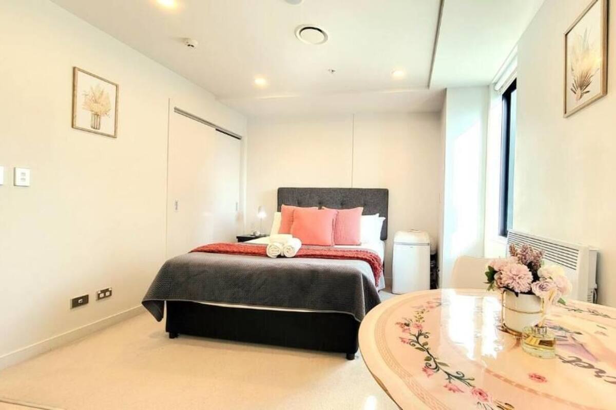 A bedroom with a bed, bedside table, and a round table with a vase of flowers.