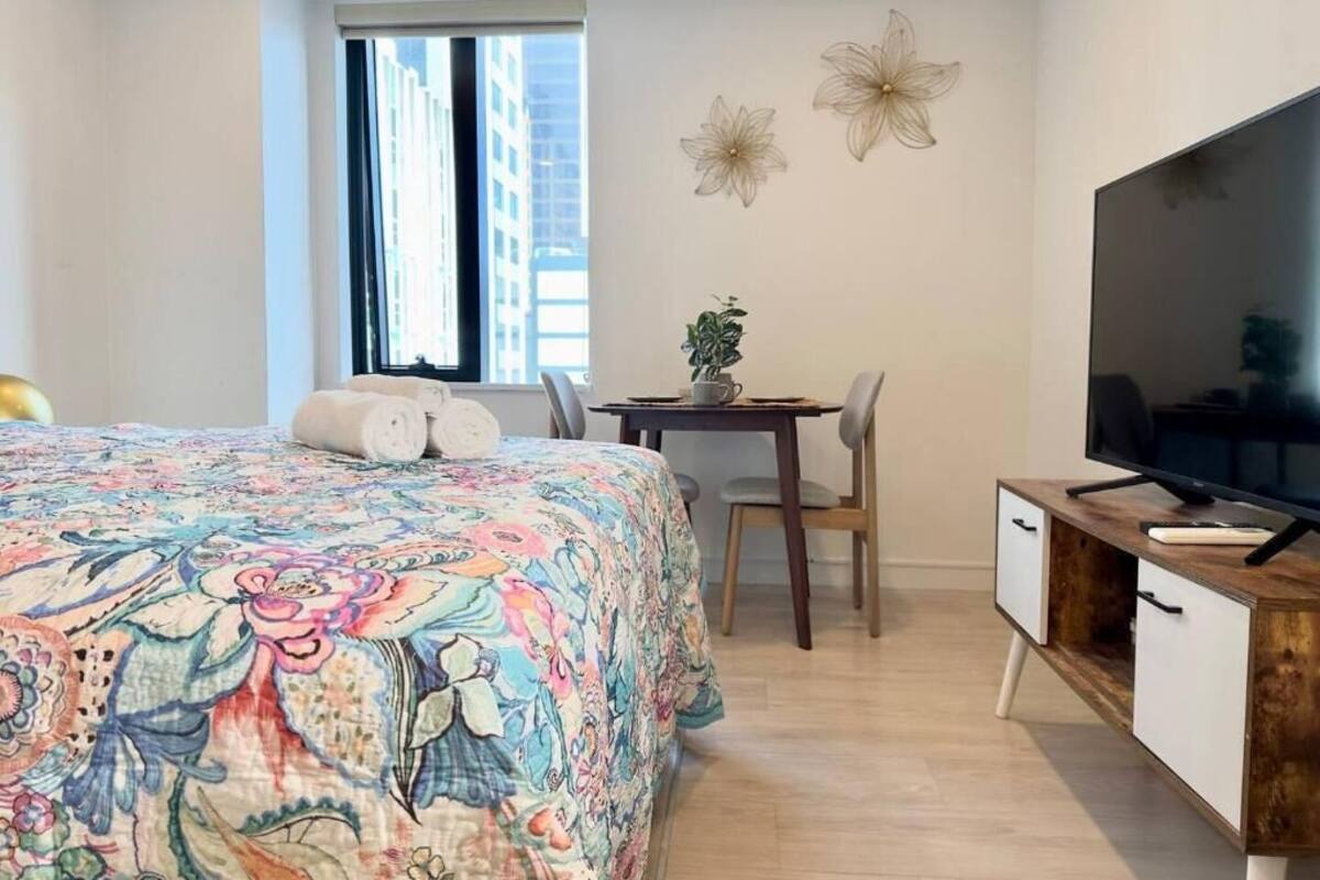 A bedroom with a bed, a desk, a chair, a television, and decorative wall art.