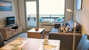 A modern living room with a sofa, a coffee table, and a television. - Lovely apartment for 3 people with WIFI, TV, balcony and pets allowed (Eckernförde)