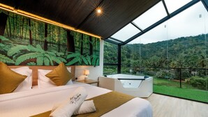 A modern hotel room with a large bed, a massage chair, and a scenic view of a forested hillside. - The Blackberry Retreat Kandy (Kandy)
