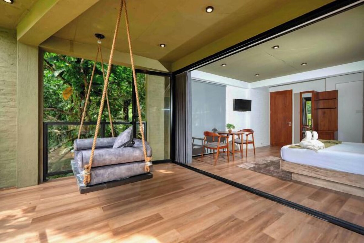 A modern bedroom with a swing chair, a bed, and a dining area with a table and chairs.