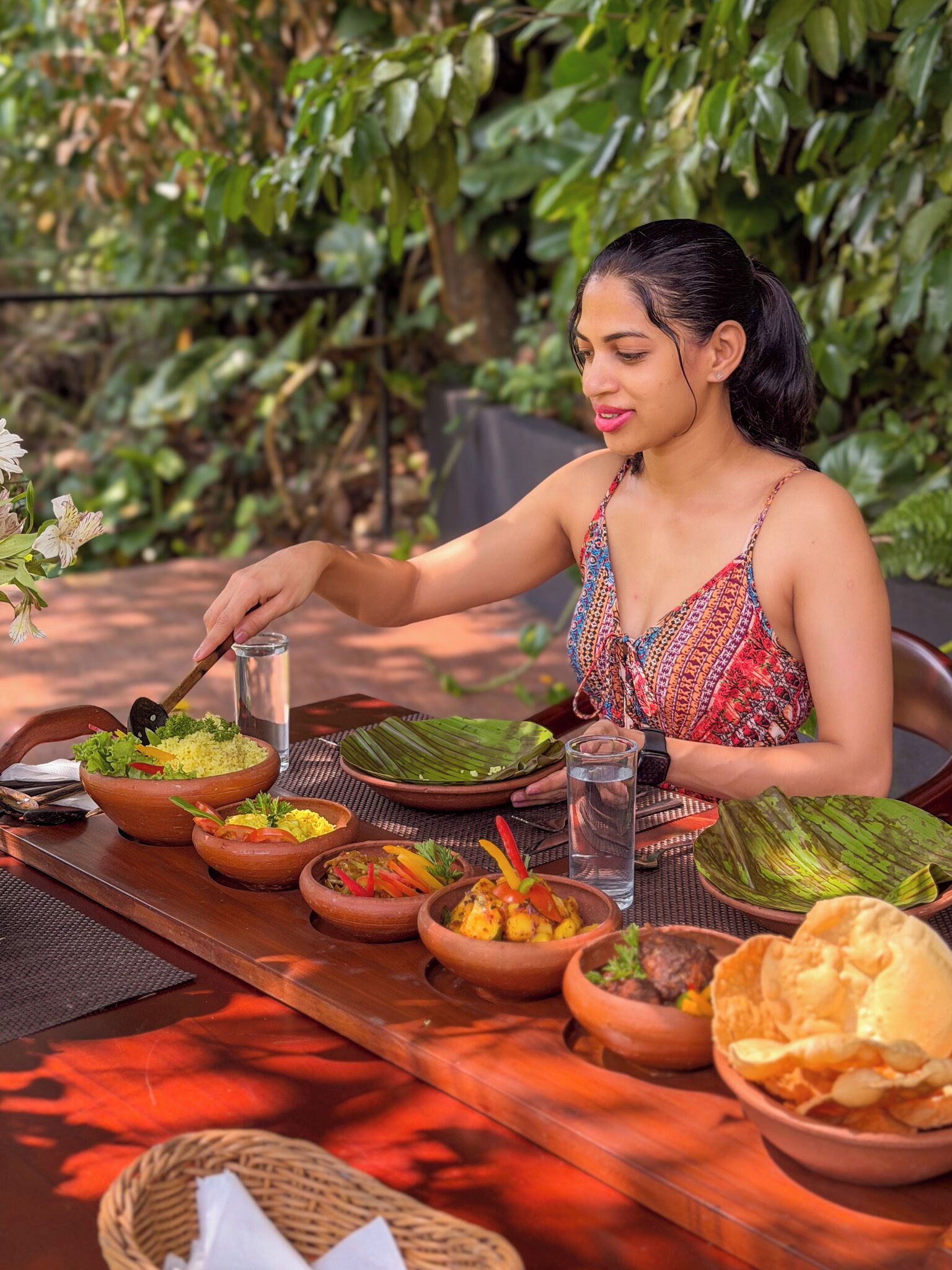 A person dining outdoors with a variety of dishes on a table.