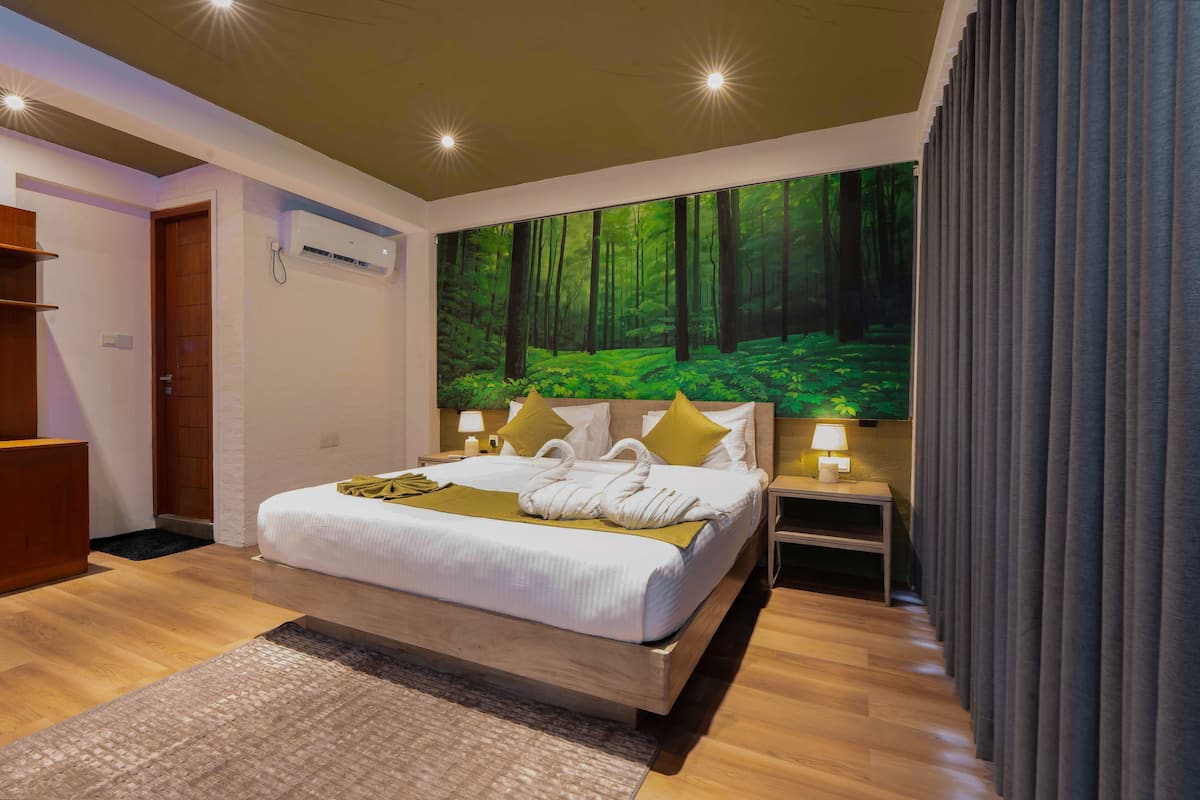 Un dormitorio moderno con una cama grande, una mesita de noche, aire acondicionado en la pared y un mural con tema de bosque.