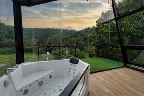 A modern spa area with a large hot tub, wooden deck, and a scenic view of a lush valley. - The Blackberry Retreat Kandy (Kandy)