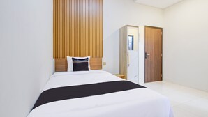 Une chambre d’hôtel avec un lit, une tête de lit en bois, une armoire et une porte.