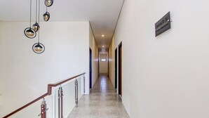 Un couloir avec un panneau indicateur, une rambarde en bois et des lampes sphériques suspendues.