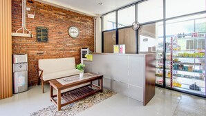 Un hall d’entrée moderne avec un mur en briques, un canapé, une table basse en bois, un réfrigérateur et une grande fenêtre donnant sur l’extérieur.