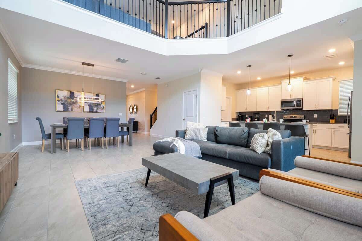 Een ruime woonkamer met een eettafel, banken en een keuken op de achtergrond.