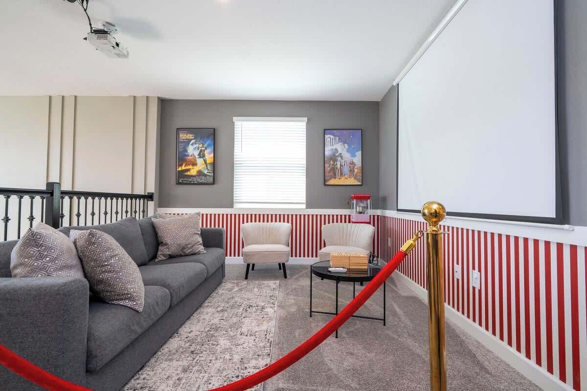 A living room with a grey sofa, two armchairs, a coffee table, and a red rope barrier.