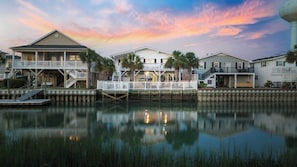 A waterfront property with multiple houses connected by walkways over water, featuring balconies and outdoor spaces.
