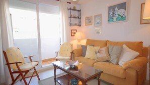 A living room with a sofa, two armchairs, a glass coffee table, and a bookshelf. - Apartment- Charly in Javea (Javea)