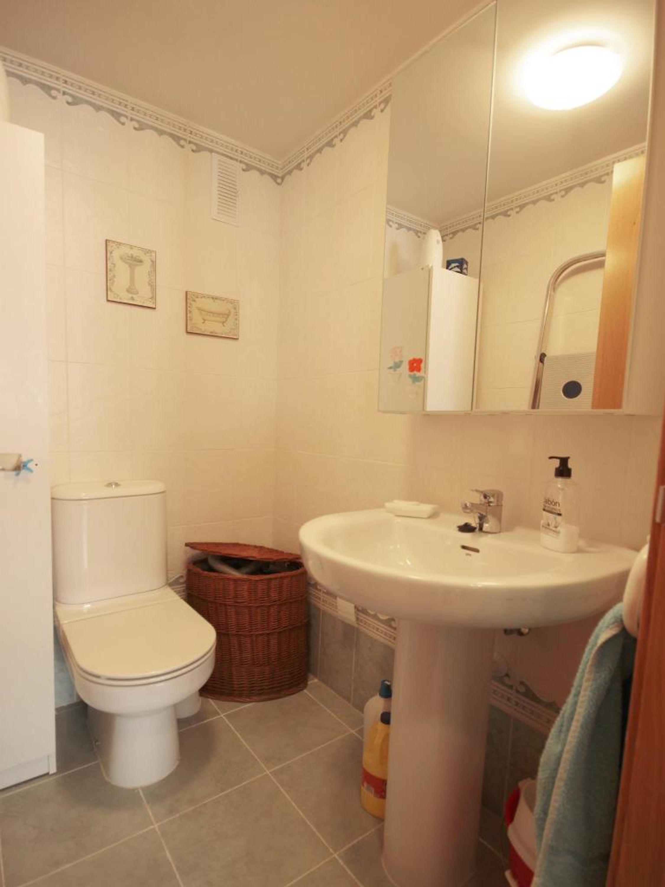 A small bathroom with a toilet, a sink, and a mirror.