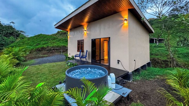 A modern house with a hot tub, a deck, and a view of a lush green landscape. - Tropical House (La Fortuna)