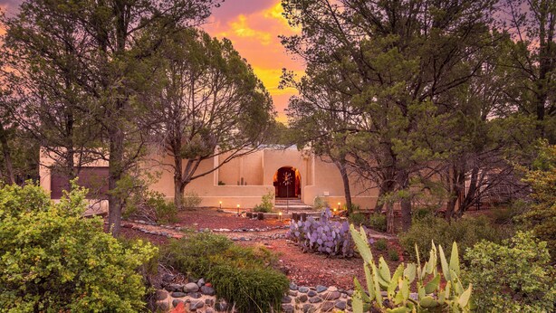 A desert-style building with a prominent entrance, surrounded by cacti and desert vegetation.