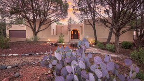 A desert-style building with a stucco exterior, a dark entrance door, and a cactus garden in the foreground.
