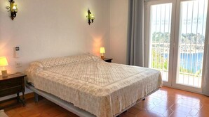 A bedroom with a bed, two bedside lamps, a nightstand, and a view of the outside through a large window. - Maria 10 in J vea With 5 Bedrooms and 3 Bathrooms (Javea)