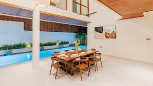 Un comedor amplio con vistas a la piscina, techo de madera y decoración moderna.