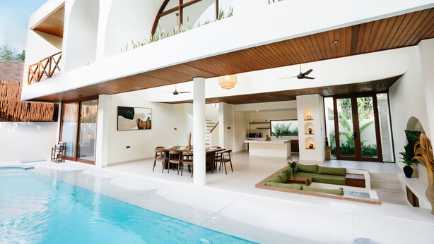 Una casa moderna con piscina, comedor y sala de estar con sofá.