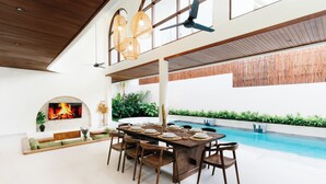Amplia zona de piscina interior con una mesa de comedor dispuesta para seis personas, rodeada de sillas.