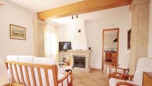 A living room with a fireplace, wooden furniture, and a television. - Villa- Caleta in Portichol (Javea)
