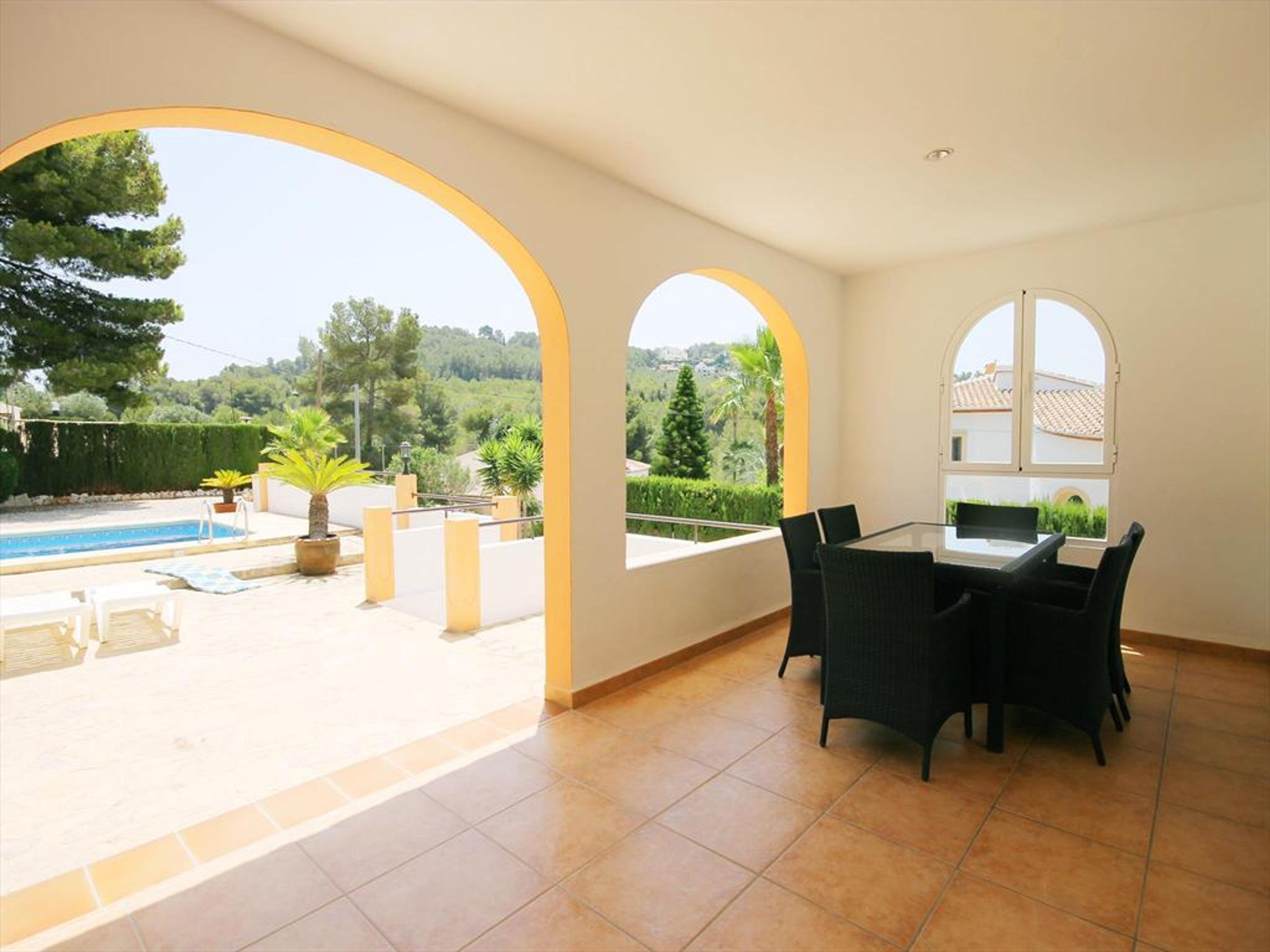 A spacious room with a pool, outdoor seating, and large windows offering a view of the countryside.