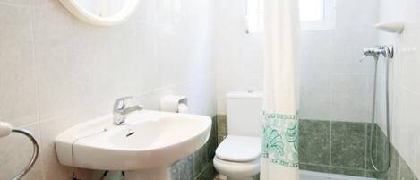 A bathroom with a sink, toilet, shower, and a mirror with lights.