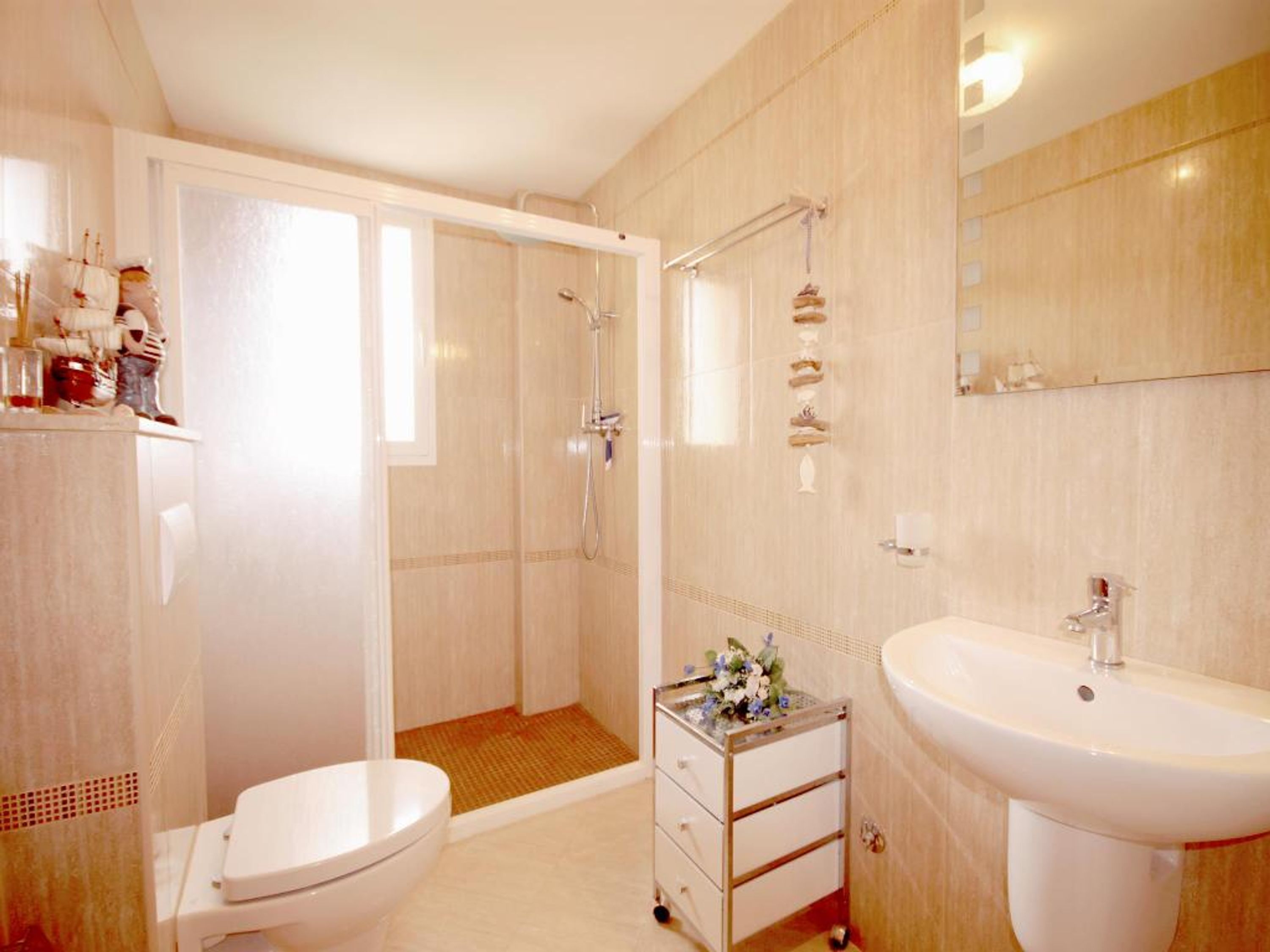 A bathroom with a toilet, a shower, a sink, and a mirror.