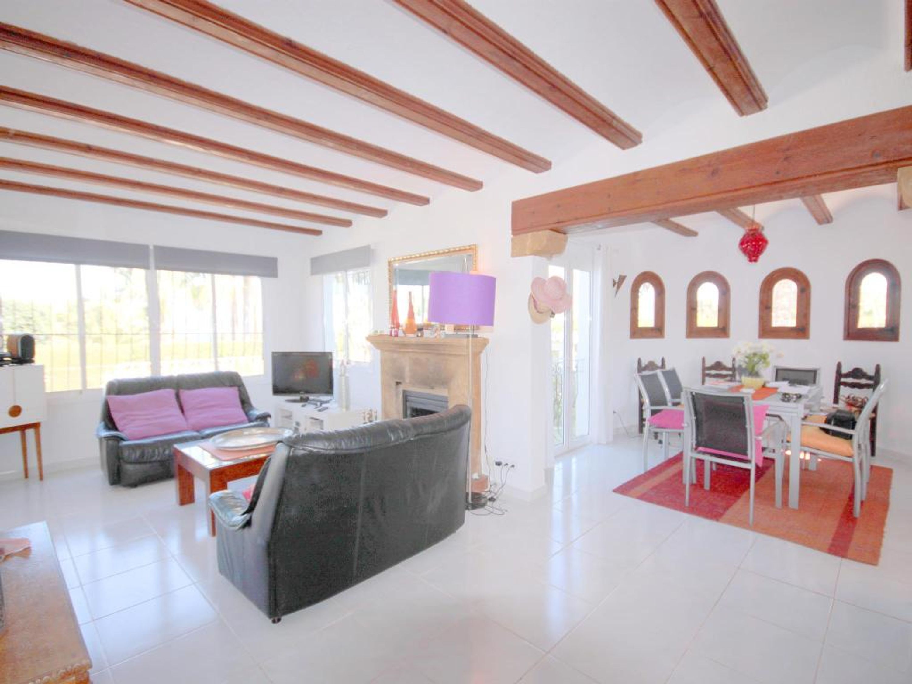 Una sala de estar amplia con chimenea, un sofá, un televisor y un comedor con sillas y una mesa.