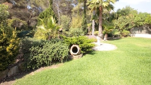 Un jardin bien entretenu, agrémenté de différents types d’arbres, d’une pelouse verdoyante et d’un mur en pierre.
