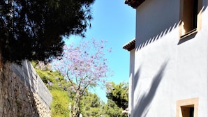 A narrow paved pathway flanked by stone walls and a white building with a window. - Villa- Impala in Javea (Javea)