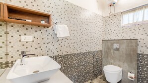 Ένα μπάνιο με λευκό νιπτήρα, τουαλέτα και χώρο για ντους.