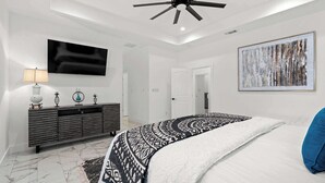 A bedroom with a bed, a ceiling fan, a TV, a dresser, and a painting. - Charming Family Getaway Near Medina River! (Bandera)