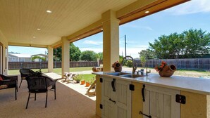 An outdoor kitchen area with a wooden ceiling, a sink, and a large planter. - Charming Family Getaway Near Medina River! (Bandera)