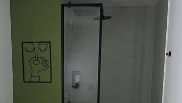 Une salle de bain comprenant des toilettes, un lavabo, une douche avec une porte en verre et un porte-serviettes avec une serviette verte.