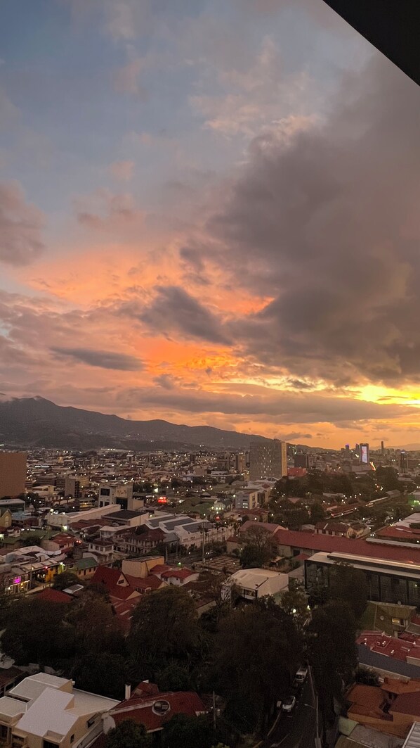 Un paisaje urbano al atardecer con edificios y una montaña al fondo.