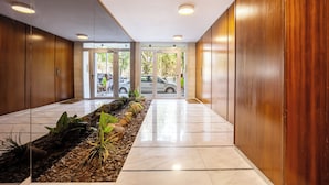 A modern hallway with wooden paneling, a tiled floor, and a plant-lined walkway.