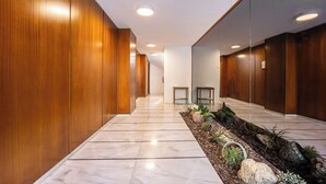 A hallway with wooden walls, marble flooring, and a small garden area with rocks and plants.