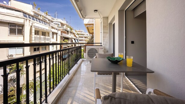 A balcony with a table, a chair, and a bowl with a drink.