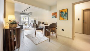 A modern interior with a dining area featuring a round table and chairs, a wooden console table with a lamp and flowers, and artwork on the walls.