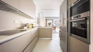 A modern kitchen with a central island, built-in oven, and a view to a dining area.