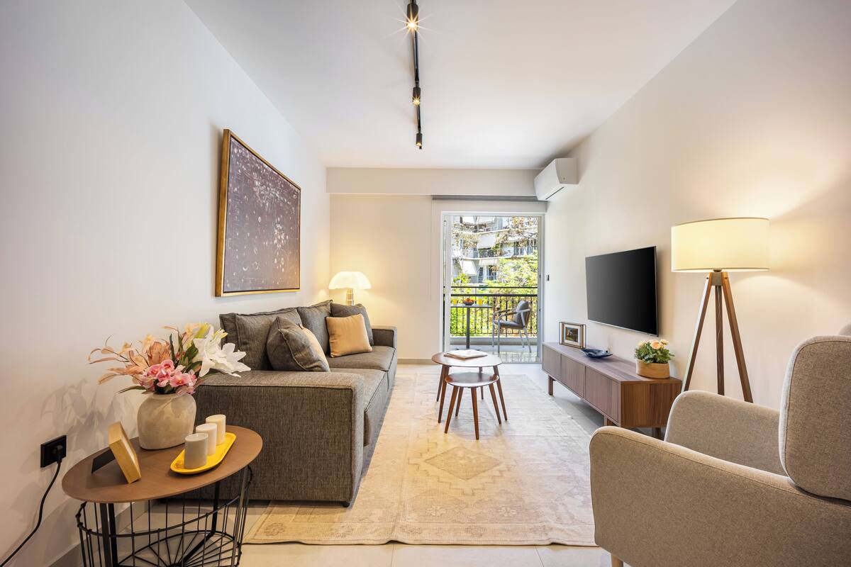 Uma sala de estar moderna com sofá, mesa de centro, televisão e varanda com vista.