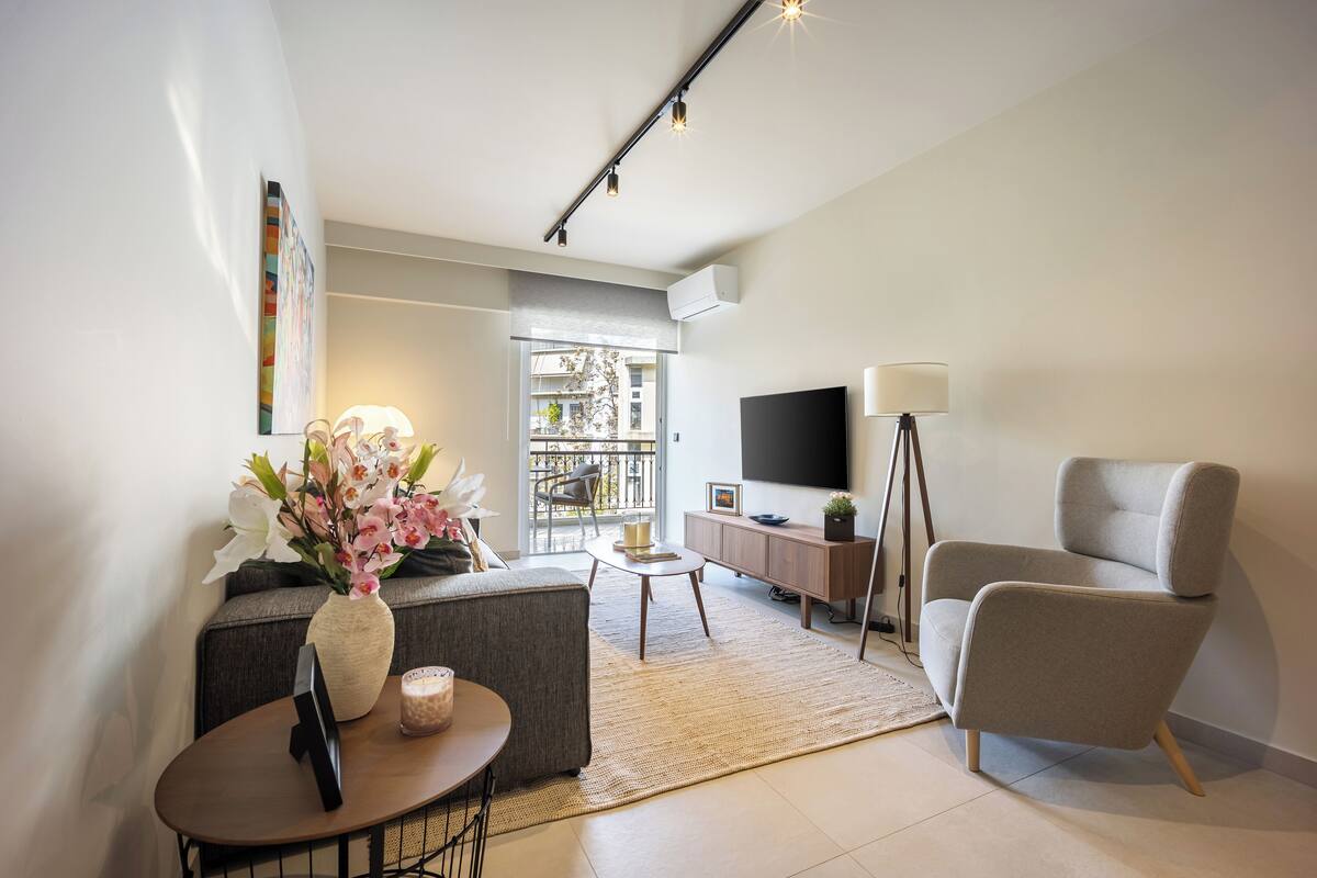 Uma sala de estar moderna com um sofá, mesa de centro e uma TV em um suporte.