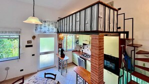 A modern kitchen with a gas stove, a dining area with a bench, and a staircase leading to an upper level. - Casa Ariel in the historic village. (Rio dell'Elba)
