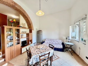 Um espaço compacto com mesa de jantar, cadeiras, pequena cozinha, armário embutido e janela com vista.