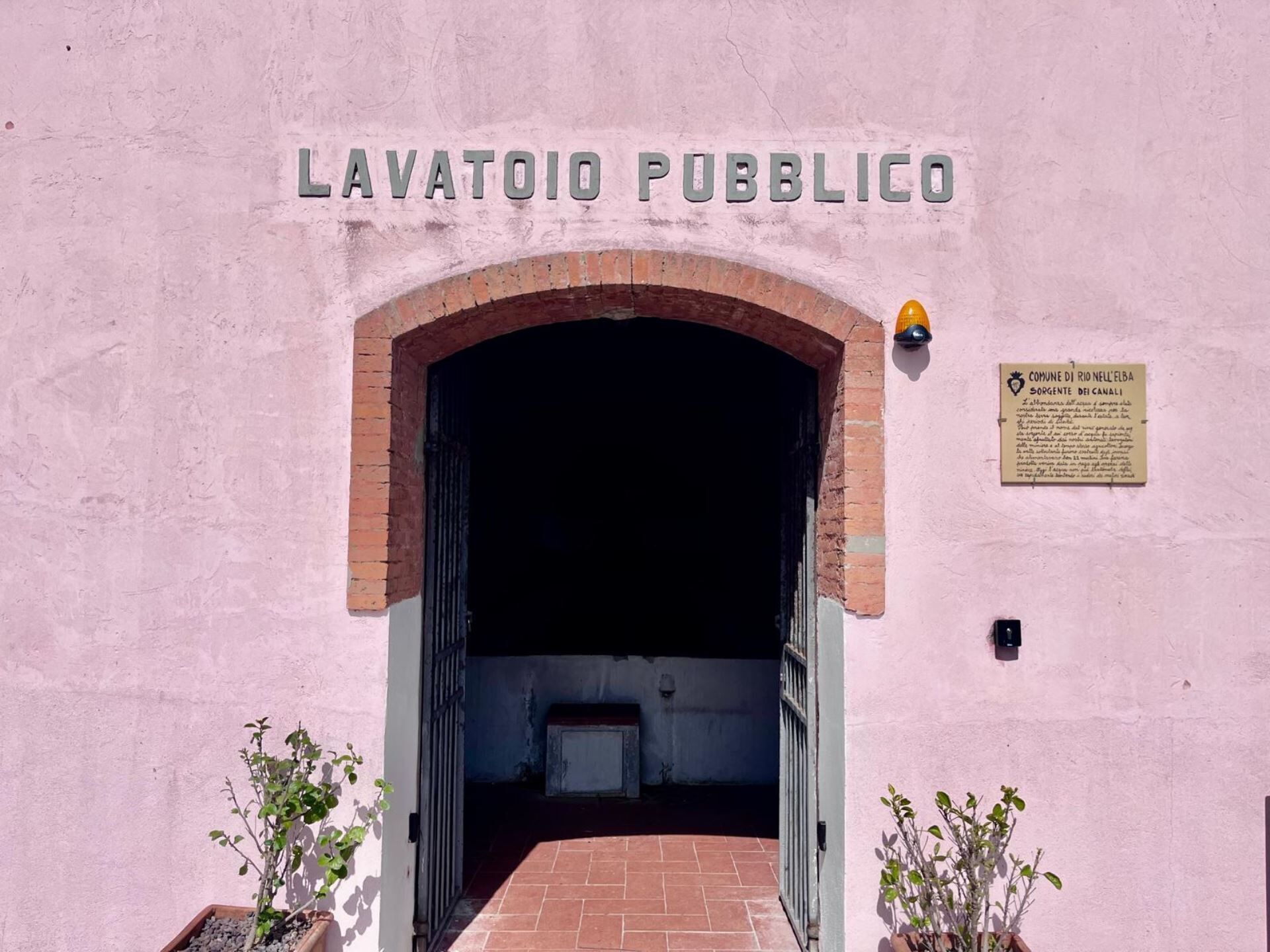 Entrada a LAVATOIO PUBBLICO con un arco de ladrillo y un cartel en la pared.